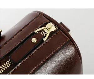 Close-up of premium brown oil wax leather texture and gold-tone metal zipper