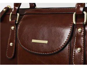 Detailed close-up of a vintage brown oil-skin leather handbag with gold hardware