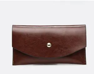Detailed view of a vintage brown oil-skin envelope clutch with a central gold snap button.