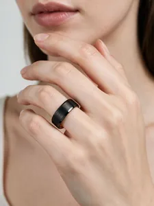 Detalle de un anillo de tungsteno negro mate con acabado de oro rosa en una mano.