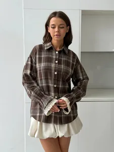 Detailed shot of retro brown plaid shirt with elegant white lace cuffs for women