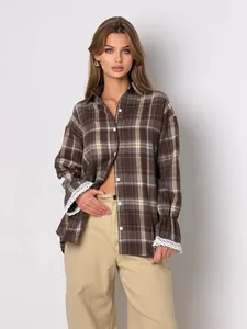 Close-up detail of brown plaid shirt featuring delicate lace trim on cuffs