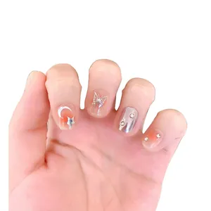 Handmade press-on nails with butterfly and moon patterns on a gradient peach base