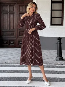 Robe mi-longue marron à pois élégante avec col à nœud papillon et manches longues.