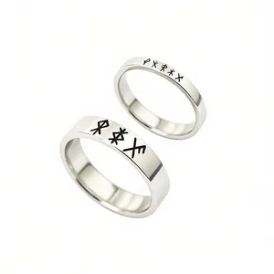 Macro view of Nordic rune engravings on minimalist stainless steel couple rings