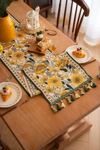 Dettaglio runner da tavola floreale jacquard con nappe colorate su tavolo di legno