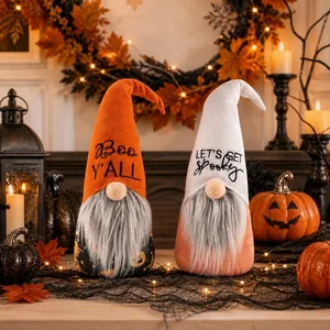 Close-up of two plush Halloween gnomes featuring embroidered festive text in a cozy setting