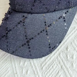 Vista macro detallada de lentejuelas y cuentas negras en una gorra de mezclilla azul marino