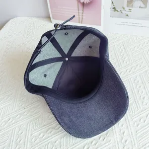 Vista interior detallada de una gorra de béisbol de mezclilla azul con costuras y correa