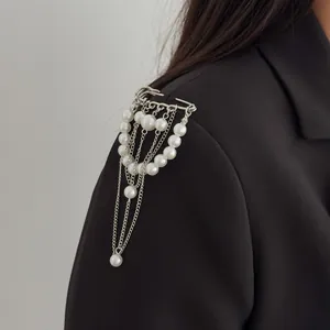 Nahaufnahme einer eleganten Schulterbrosche mit Perlen und Ketten auf schwarzem Blazer