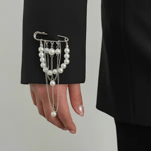 Detailansicht einer eleganten Brosche mit Kunstperlen und Quasten an einem Ärmel.