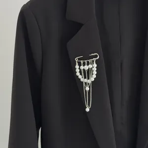 Detailansicht einer eleganten Brosche mit Kunstperlen und Quastenkette auf einem schwarzen Anzug