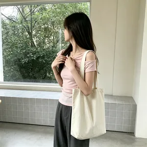 Large capacity cream canvas tote bag worn by a model in a casual setting