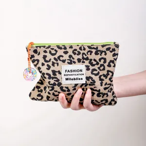 Borsa cosmetica in tela leopardata con cerniera verde neon e ciondolo a forma di ciambella