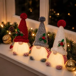 Detailed view of three handmade glowing Christmas gnomes with knit hats on a windowsill