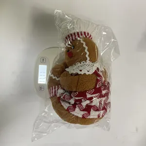 Close-up of a gingerbread man plush Christmas decoration being weighed on a white digital scale