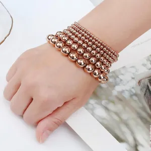 Primo piano di braccialetti elastici con perle in acciaio inossidabile oro rosa