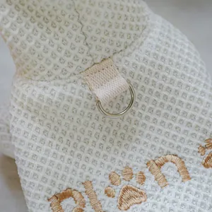 Detail view of white pet hoodie with metal D-ring and golden paw embroidery