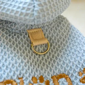 Detailed macro view of the metal D-ring attachment on a blue textured pet dog winter hoodie