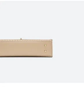 Vue détaillée du fond d'un sac à main beige tissé avec des clous de protection dorés