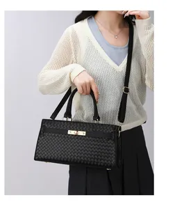 Vue détaillée d'un sac à main noir à texture tissée porté en bandoulière par un modèle