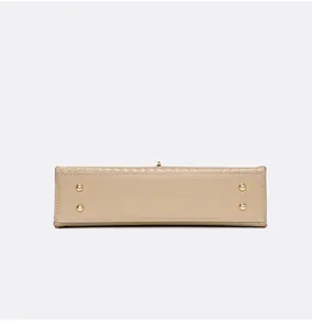 Vue de dessous d'un sac à main beige tressé avec pieds de protection en métal doré