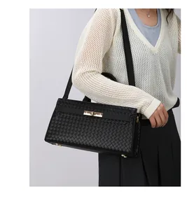 Vue détaillée d'un élégant sac à main noir à texture tissée porté par un mannequin