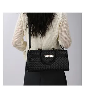 Vue détaillée du sac à main noir à texture tressée avec fermoir élégant en métal doré chic.