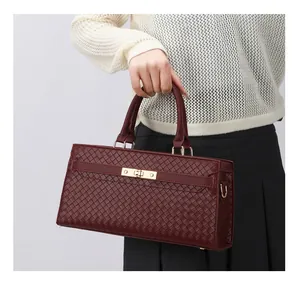 Vue détaillée d'un sac à main tissé bordeaux avec ses finitions dorées élégantes