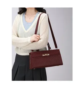 Vue détaillée d'un élégant sac à bandoulière bordeaux à texture tressée sur un modèle