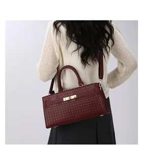 Vue détaillée d'un sac à main bordeaux à texture tressée avec garniture dorée