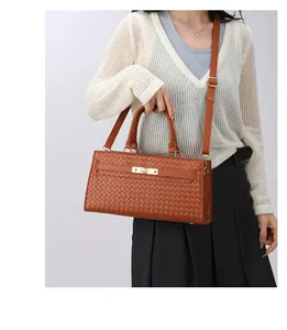 Détail d'un sac à main marron à texture tressée avec fermoir doré porté par un mannequin
