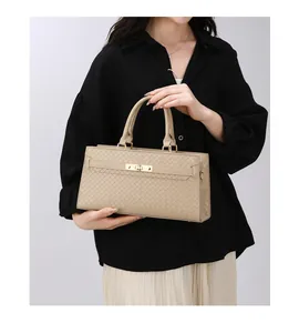 Détail d'un sac à main beige à texture tissée porté par un mannequin élégant.