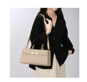 Gros plan d'un sac à main beige tendance avec texture tissée porté par un mannequin en studio