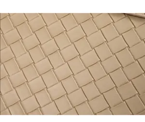 Gros plan détaillé montrant la texture tissée beige complexe d'un sac à main en cuir de luxe