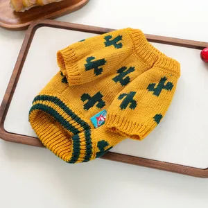 Macro view of yellow knitted pet sweater featuring green cactus patterns for small dogs and cats