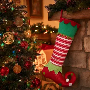 Detail view of festive red and green striped elf Christmas stocking on a fireplace