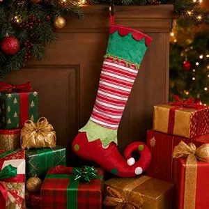 Large elf-style Christmas stocking hanging among festive gift boxes and warm lights