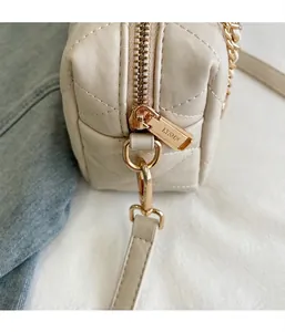 Macro-opname van gouden rits en gewatteerd leer op elegante beige kussentas