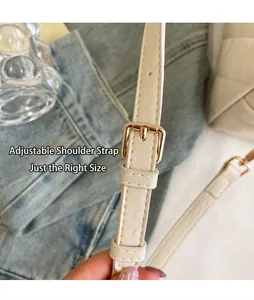 Detailopname van de verstelbare gouden gesp op een crème gewatteerde leren crossbodyband