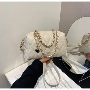 Detail van beige gewatteerde leren kussentas met gouden ketting en hartjeshanger