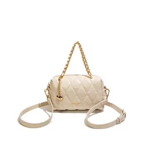 Elegante gebroken witte gewatteerde kussentas met gouden ketting en hartdetail.