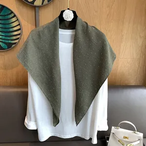 Gros plan sur un foulard en lin et coton vert foncé orné de strass en forme d'étoiles