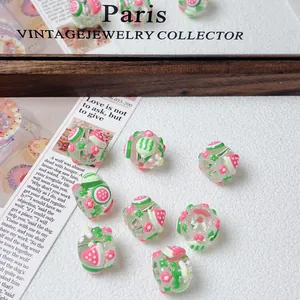 Close-up detail of cute hand-painted strawberry and watermelon glass beads for DIY jewelry.