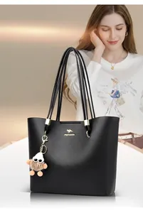 Elegant black leather tote bag for women with thin straps and a cute plush charm accessory