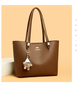 Elegant brown leather tote bag with minimalist design and decorative doll charm