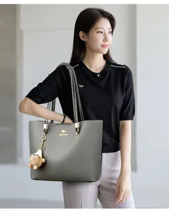 Large gray leather tote bag shown on a model, ideal for professional commuting style.