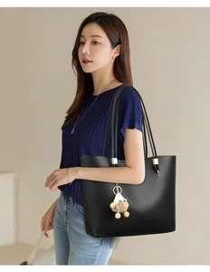 Detail showing a minimalist black large-capacity tote bag worn by a model for a commuter look.