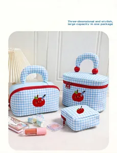 Detailed view of blue and white checkered cosmetic bags featuring cute apple embroidery