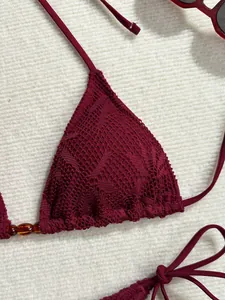 Gros plan sur le haut de bikini triangle en dentelle bordeaux avec perles ambrées